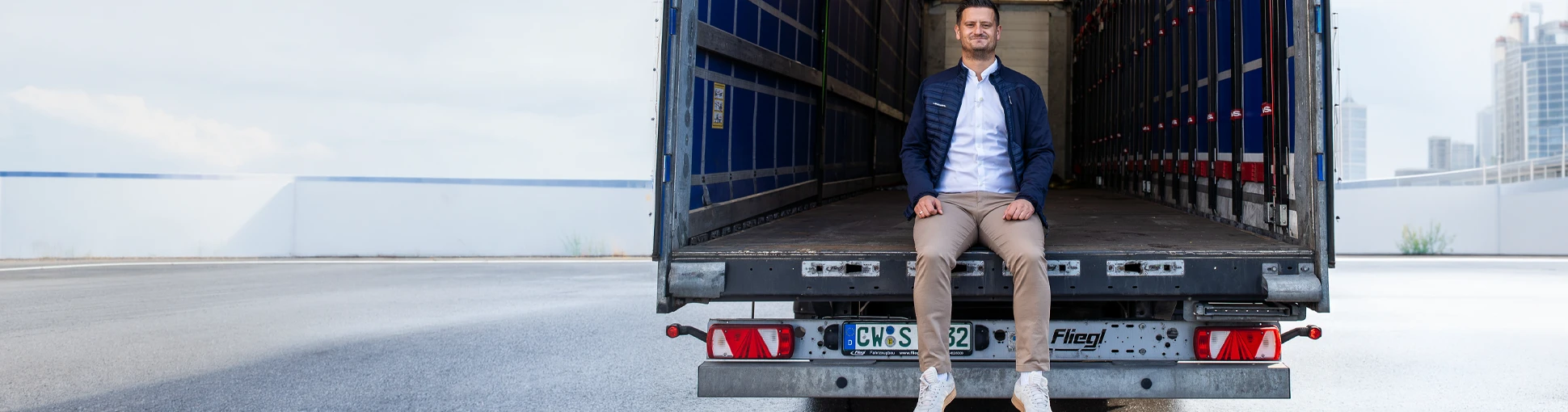 Person sitzt hinten auf der Ladefläche eines Schuon LKWs für Transport